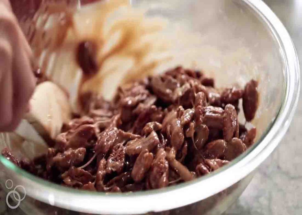 Mixing the pecans with the butter mixture