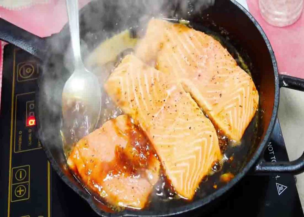 Basting the salmon to its honey garlic sauce