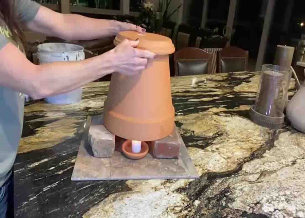 Placing the clay pot on top of the candles