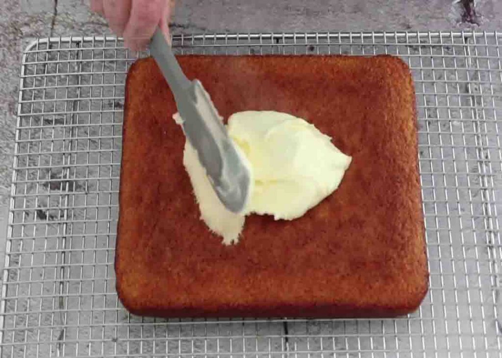 Spreading the icing over the coconut lemon cake