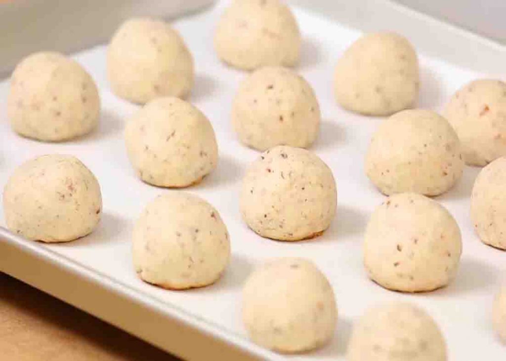 Placing the snowball cookies on a baking sheet