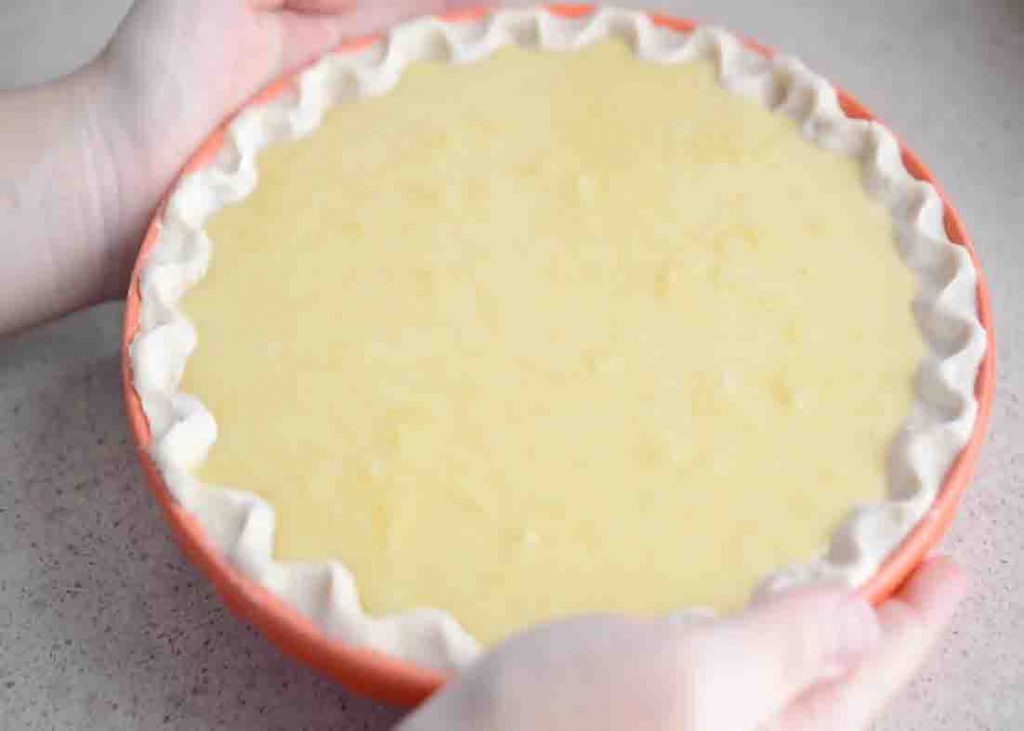 Pouring in the lemon buttermilk pie filling to the unbaked pie crust
