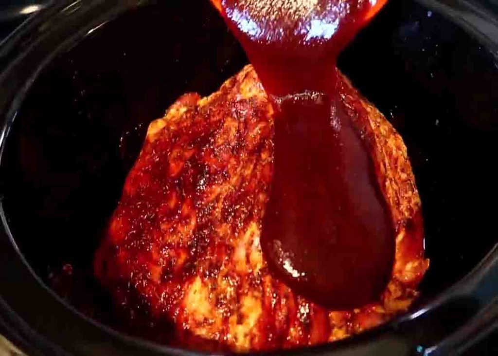 Pouring the bbq sauce over the ribs in the slow cooker