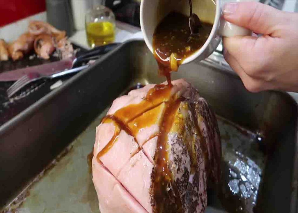 Pouring the sticky sauce over the coke-soaked ham