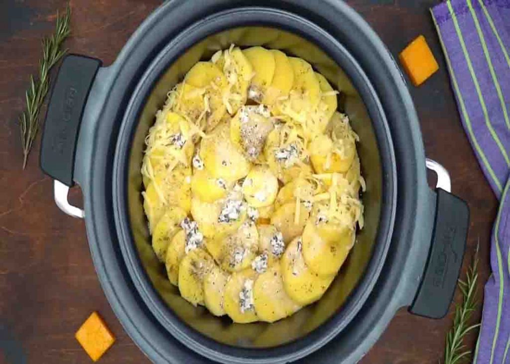 Arranging the sliced potatoes to the slow cooker