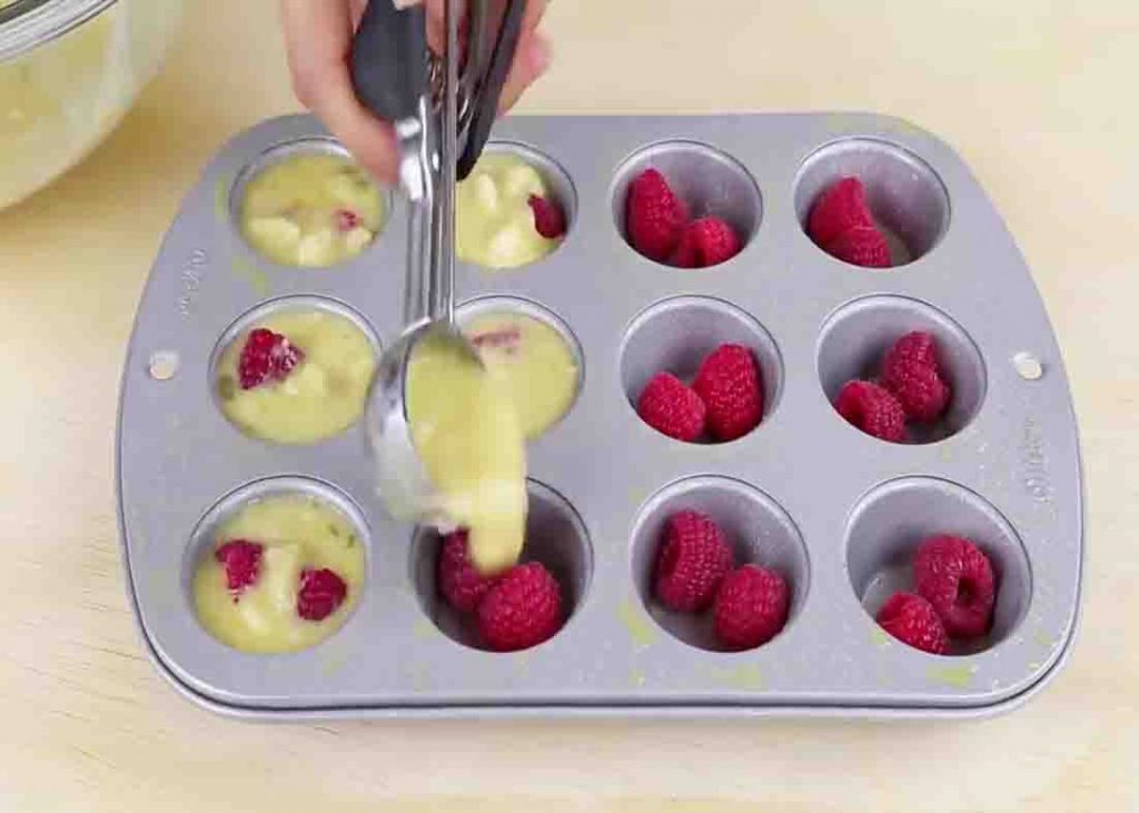 Filling the muffin cups with berries and egg mixture