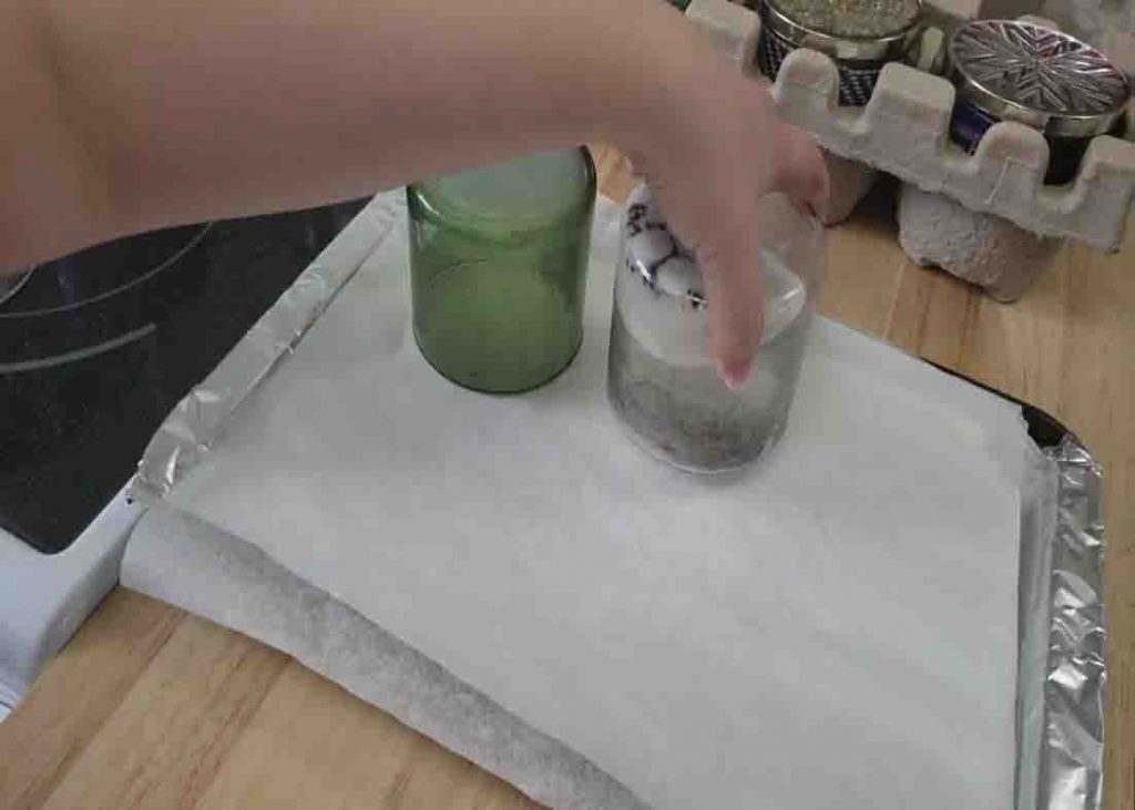 Putting the glass jars into a preheated oven for 15 minutes to remove the candle wax