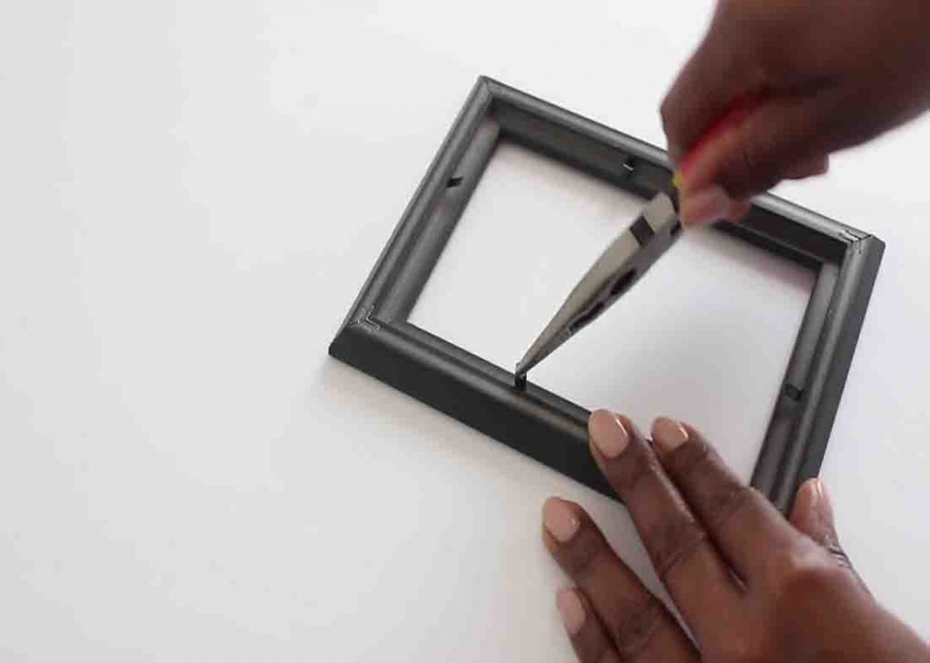 Removing the tabs from the frame to make the DIY mirror wall decor