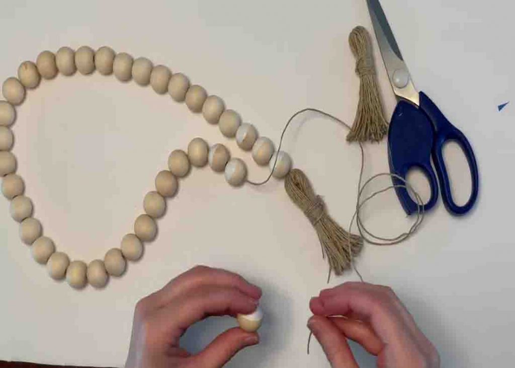 Putting the wood beads through the twine