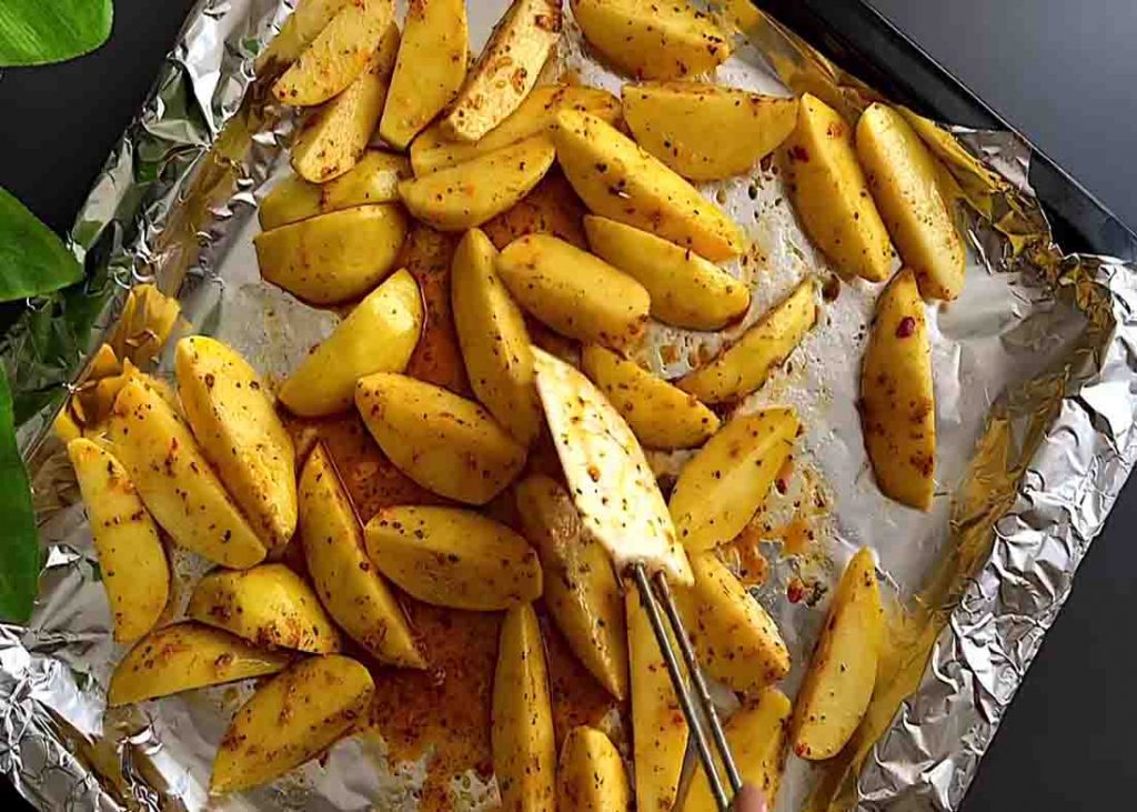 Putting the potato wedges into the lined baking tray for baking
