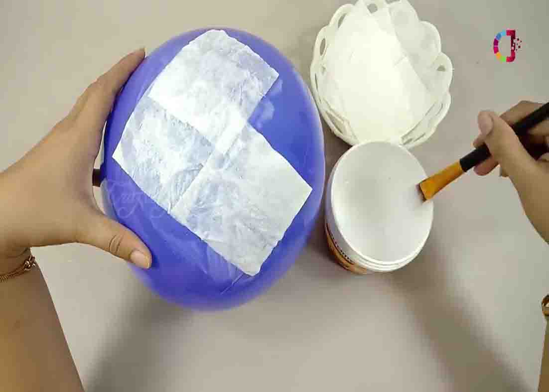 Putting glue and tissue paper all over the balloon for the DIY moon lamp