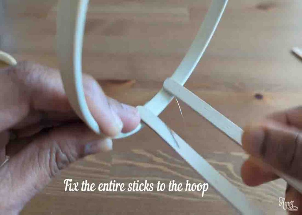 Gluing the popsicle sticks to the hoop to make the candle holder