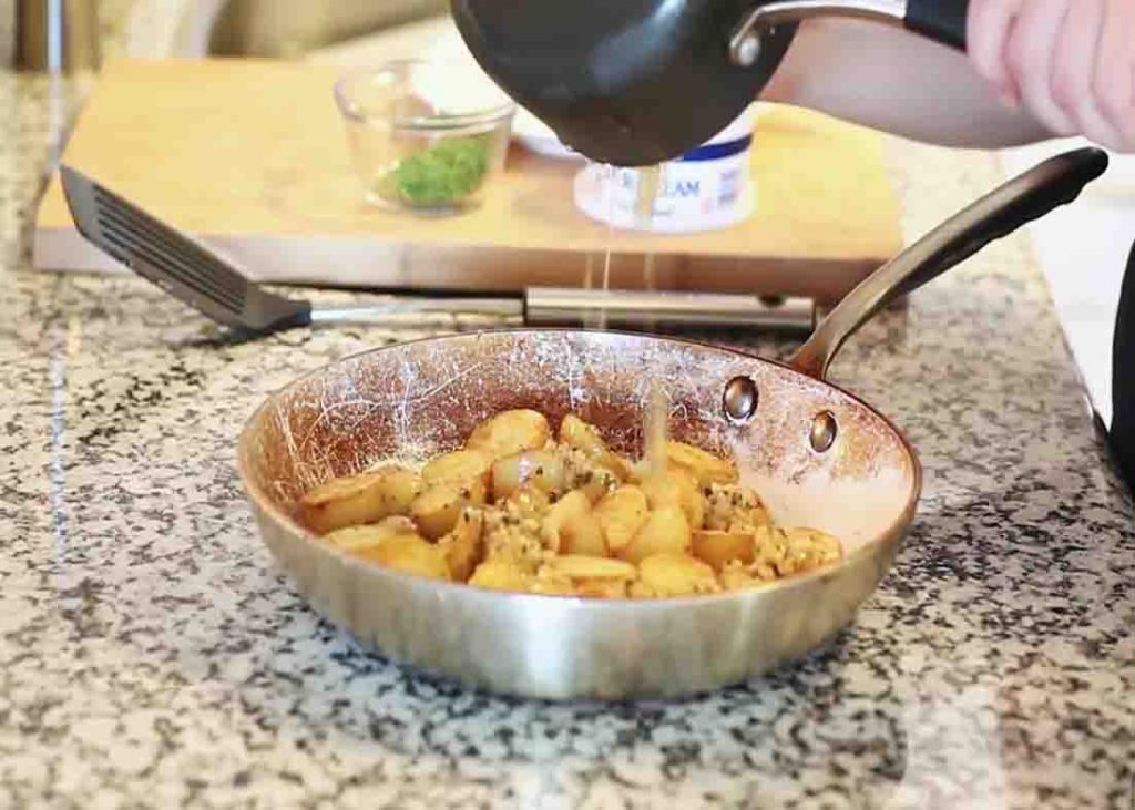 Pouring the garlic sauce over the baby potatoes
