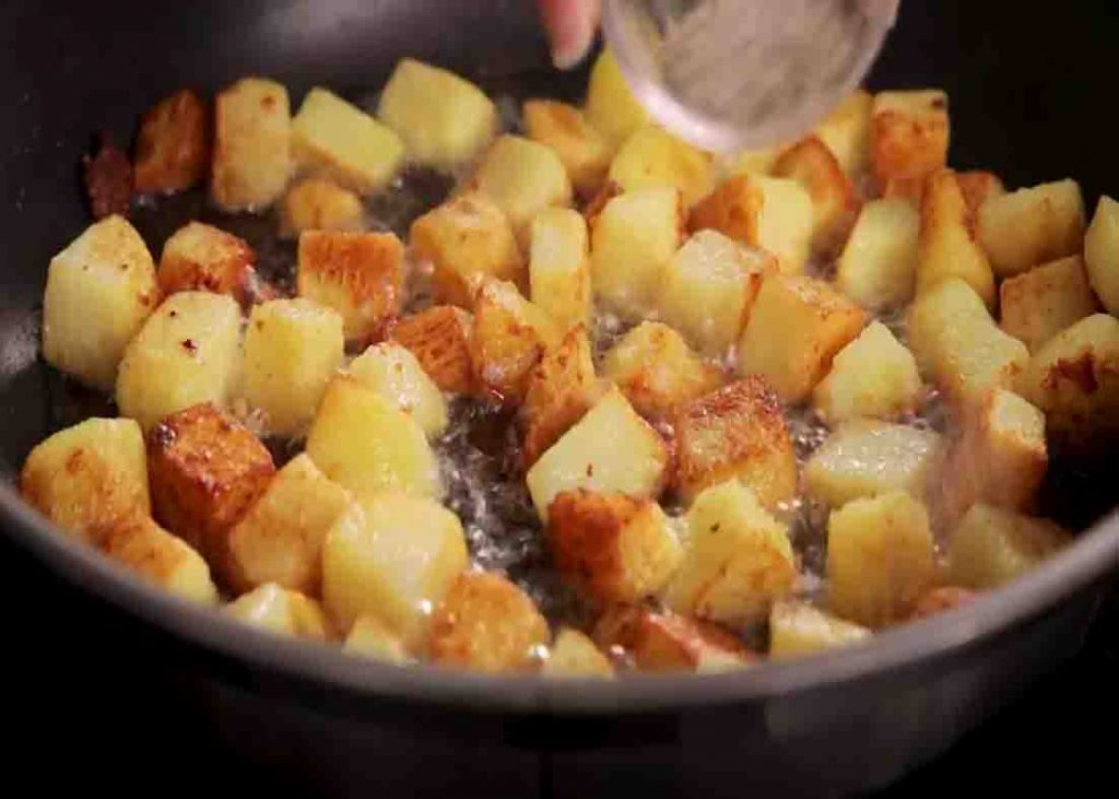 Frying the potatoes in the pan with minced garlic