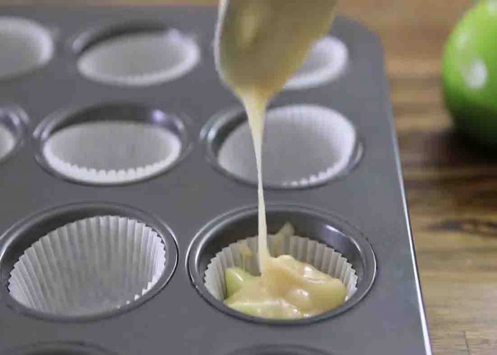 Putting the apple crumble batter to the muffin cups