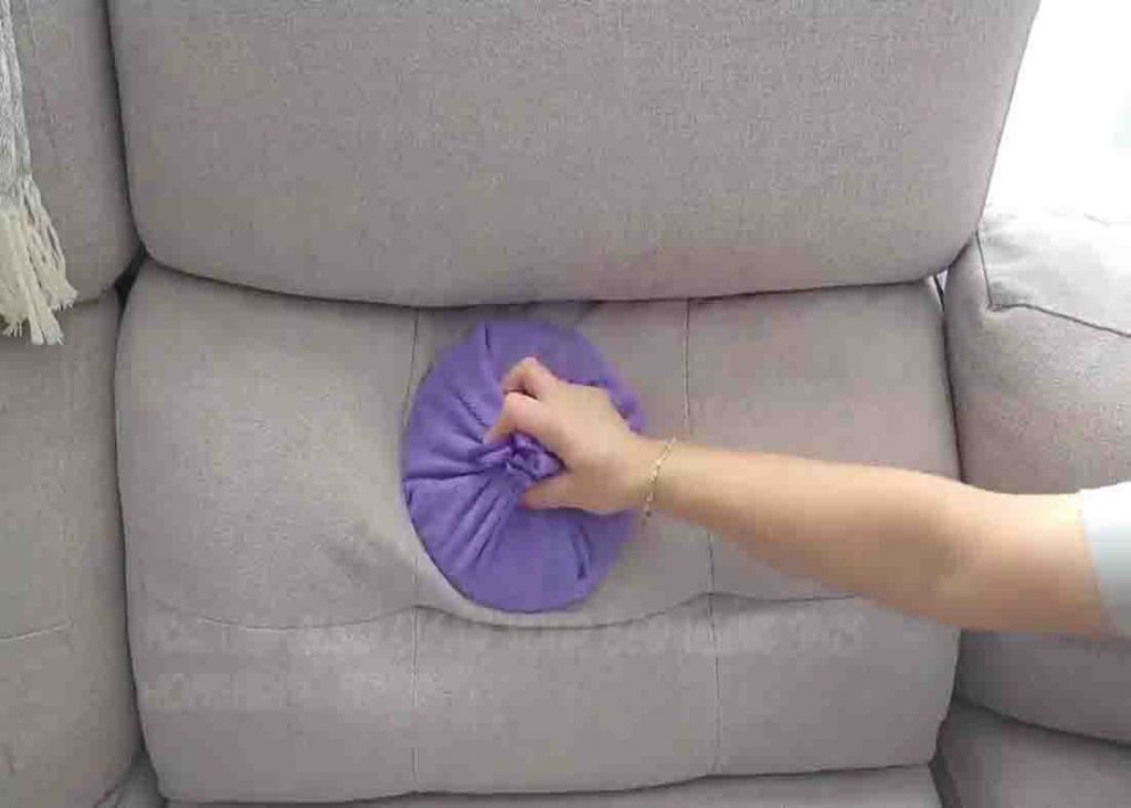 Cleaning the couch with pot lid and microfiber cloth