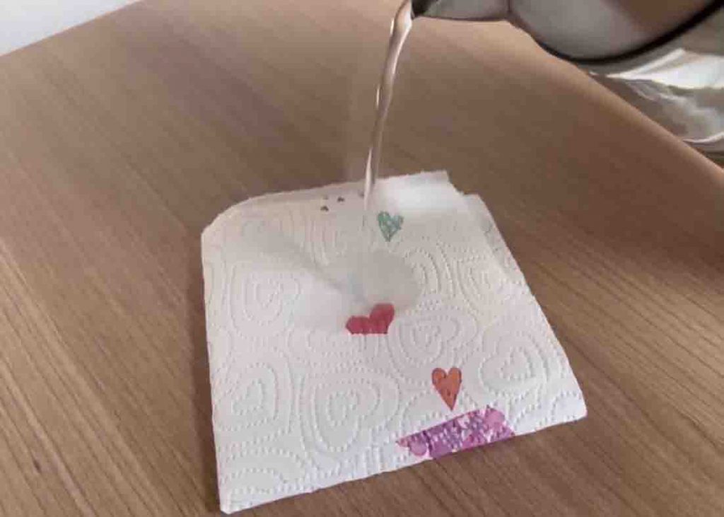 Pouring hot water over the paper towel to remove the candle wax
