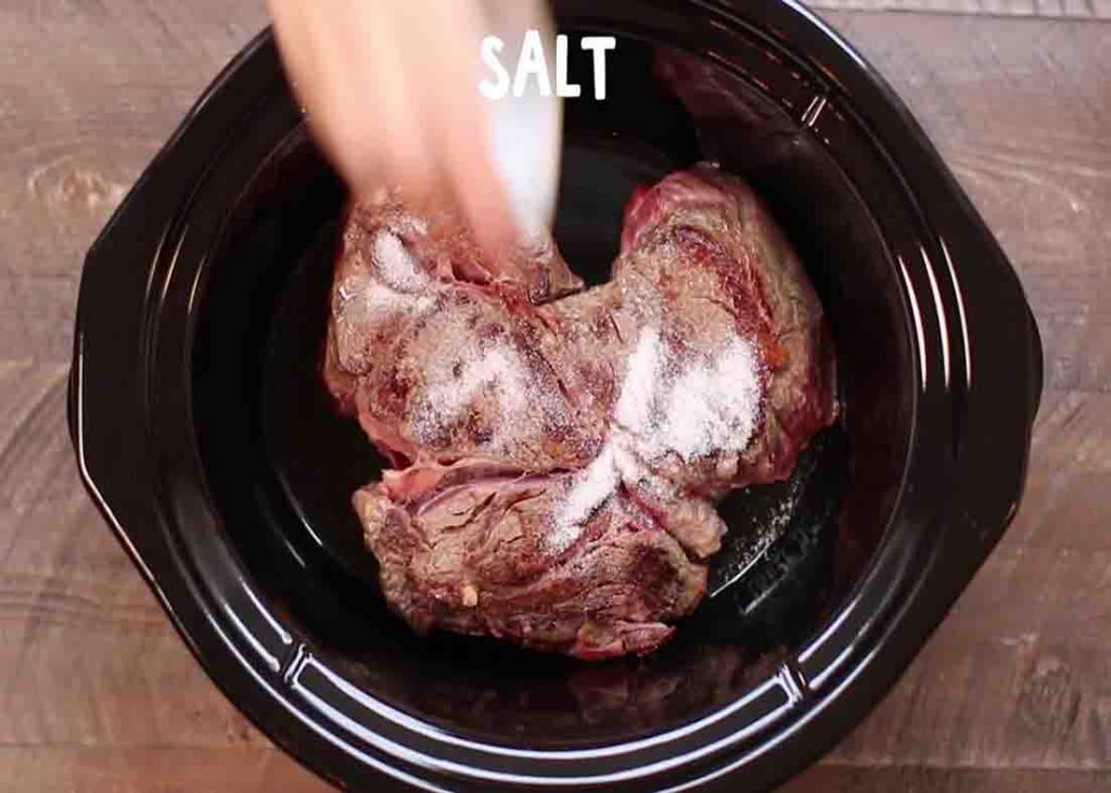 Seasoning the beef chuck roast in the slow cooker