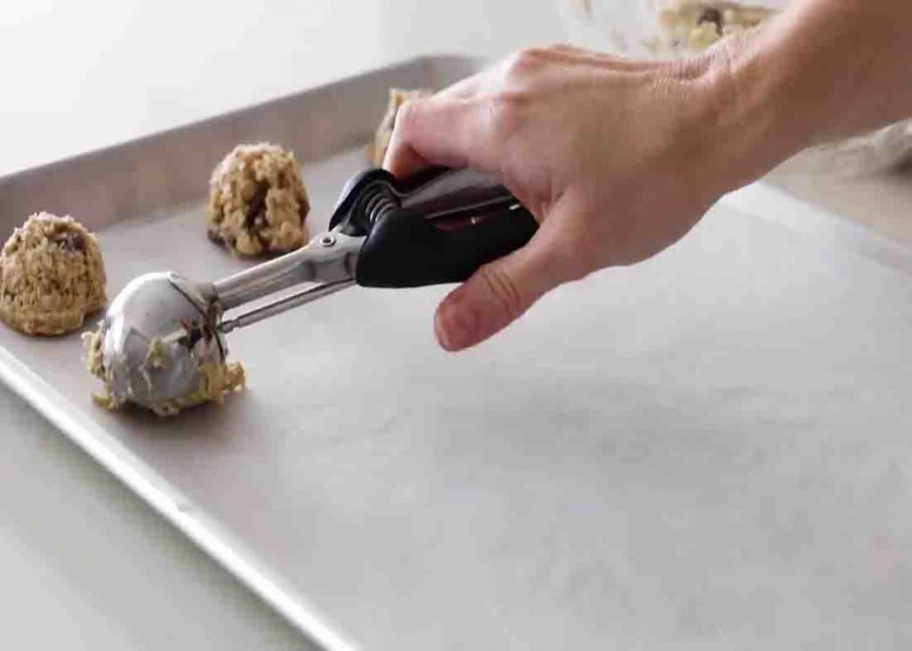 Scooping the banana oatmeal cookies mixture to the baking tray