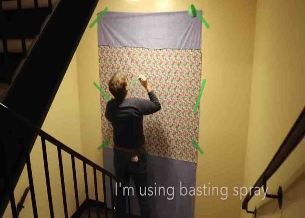 Using masking tape to hang your backing, batting, and fabric on the wall and keep them secured