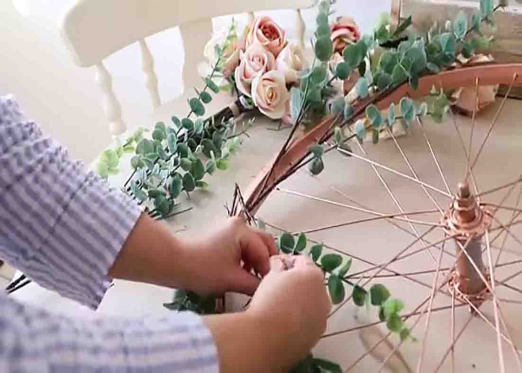 Attaching the faux flowers to the repurposed bike wheel