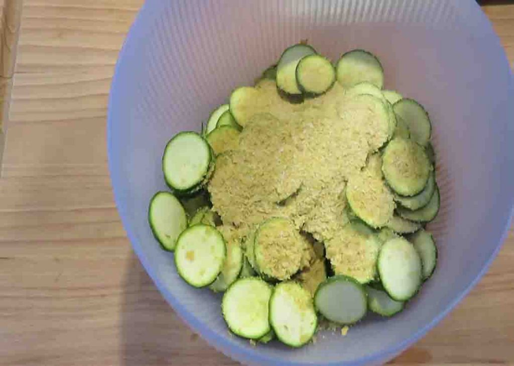Seasoning the thinly sliced zucchini before air frying