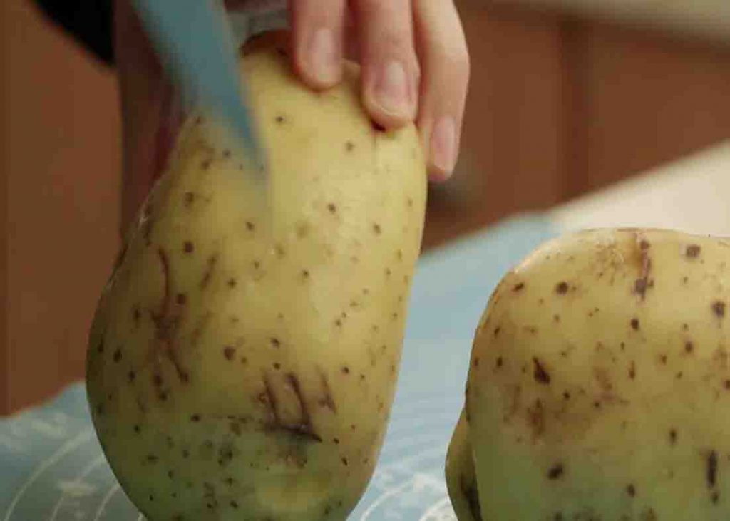 Cutting the blemishes on the potatoes before baking