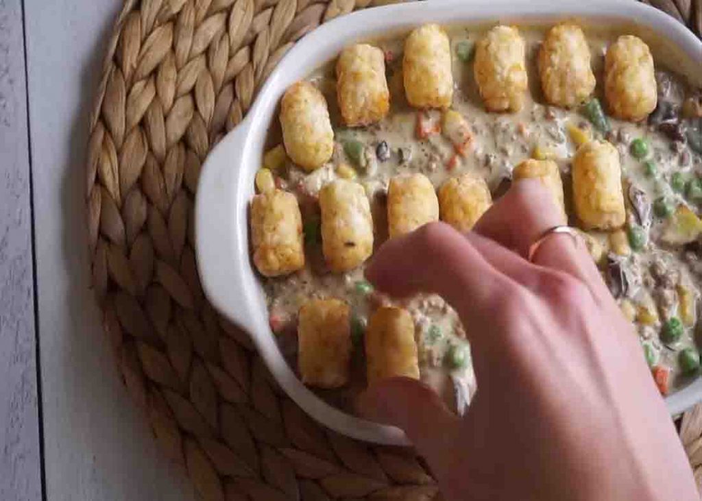 Putting the tater tots over the casserole dish