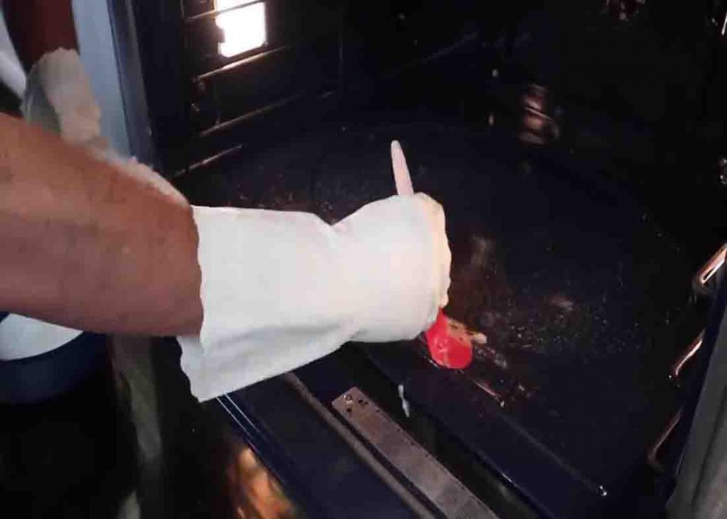 Spreading the baking soda paste on the dirty oven