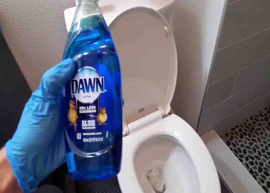 Pouring the dish soap into the toilet bowl to de-clog it