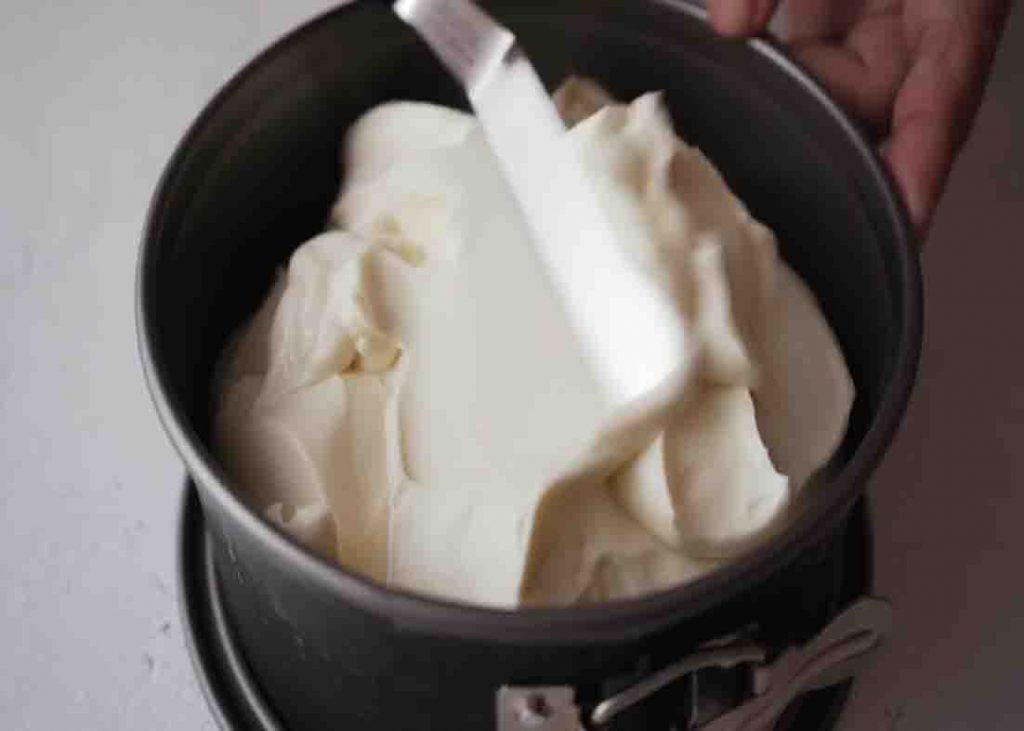 Spreading the cheesecake mixture to the pan evenly.