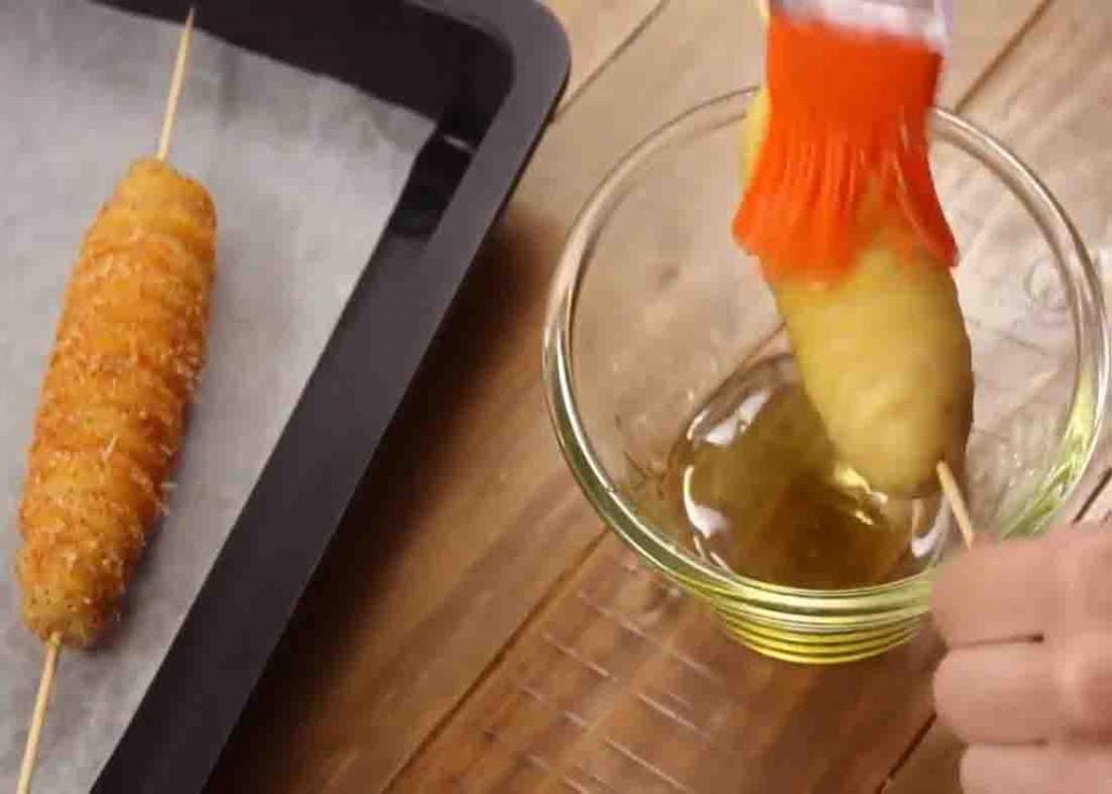 Brushing the tornado potato with olive oil