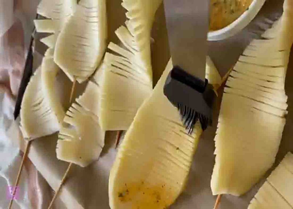 Spreading the herb garlic butter onto both sides of the potatoes