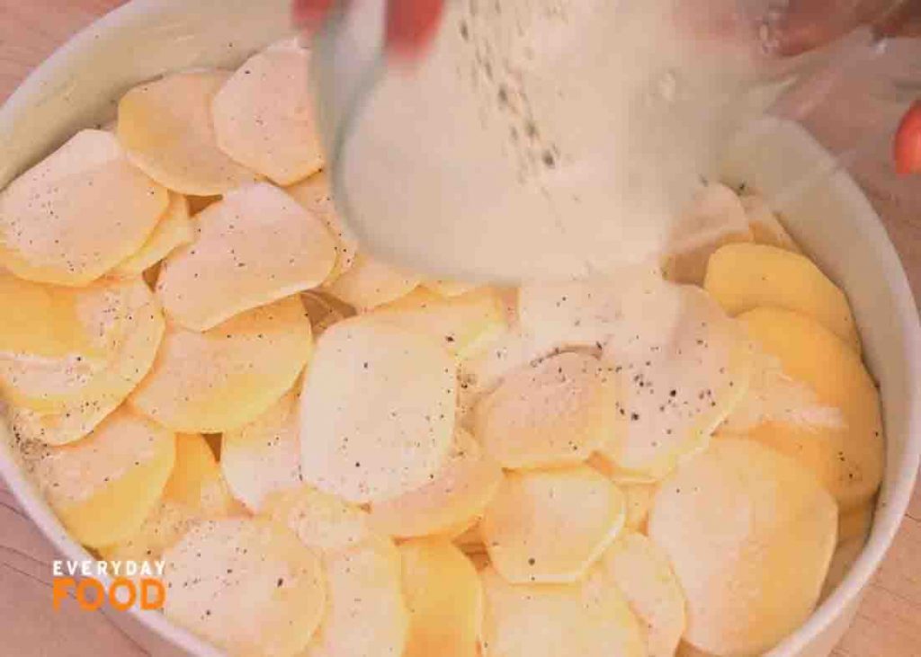 Pouring the milk mixture on top of the potatoes