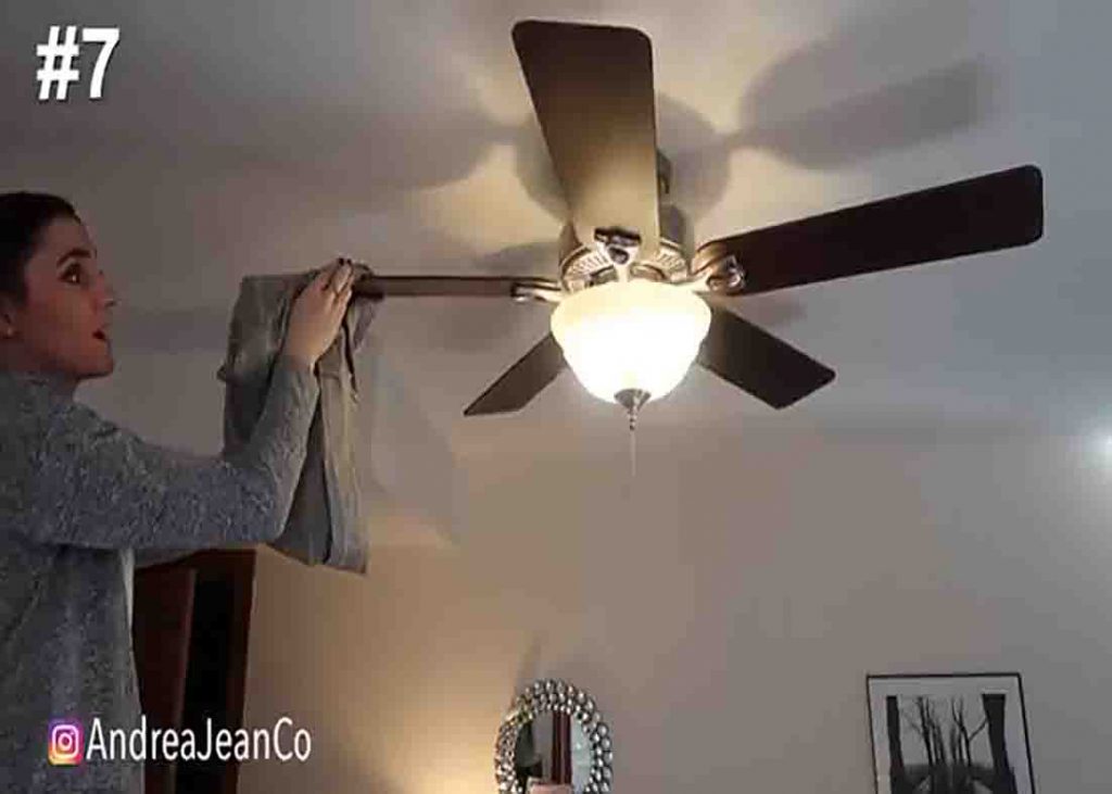 Cleaning the ceiling fan blades with old pillowcase