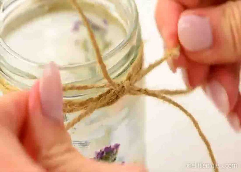Looping the twine around the mouth of the mason jar