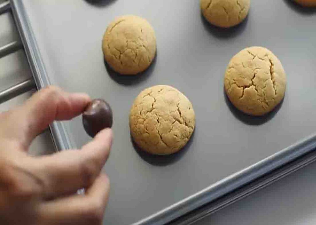 Adding the kisses on top of each peanut butter cookies