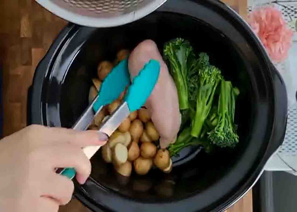 Adding the veggies and chicken to the slow cooker