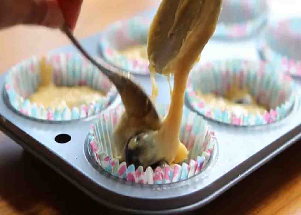Dividing the muffin batter to each cupcake liner