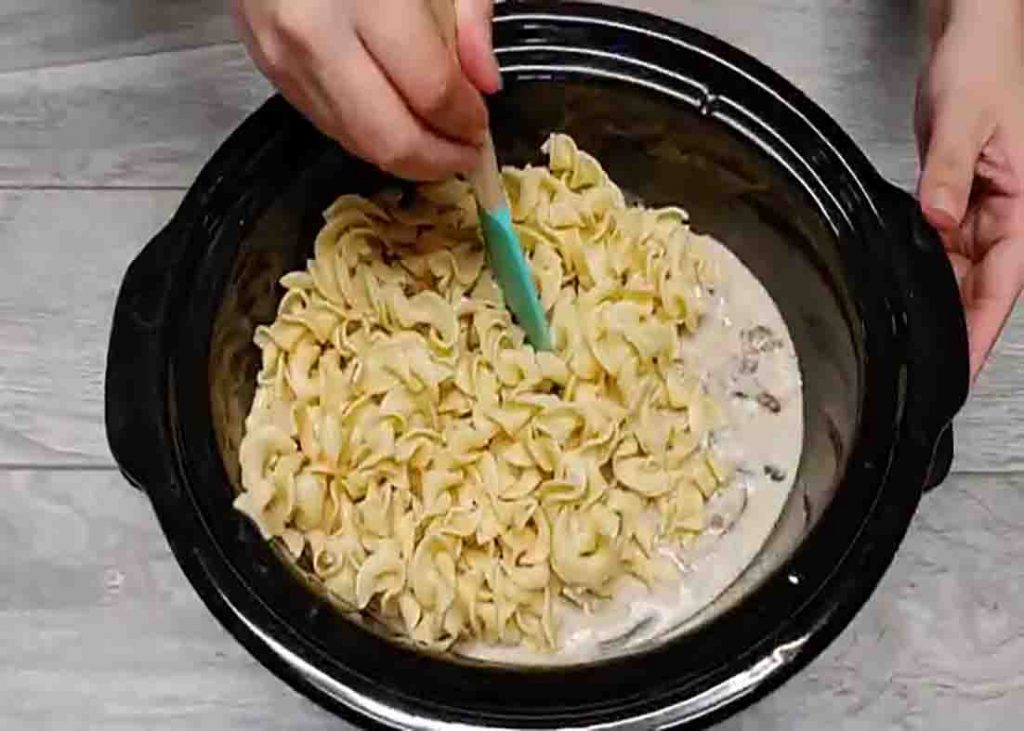 Adding the egg noodles to the crock pot