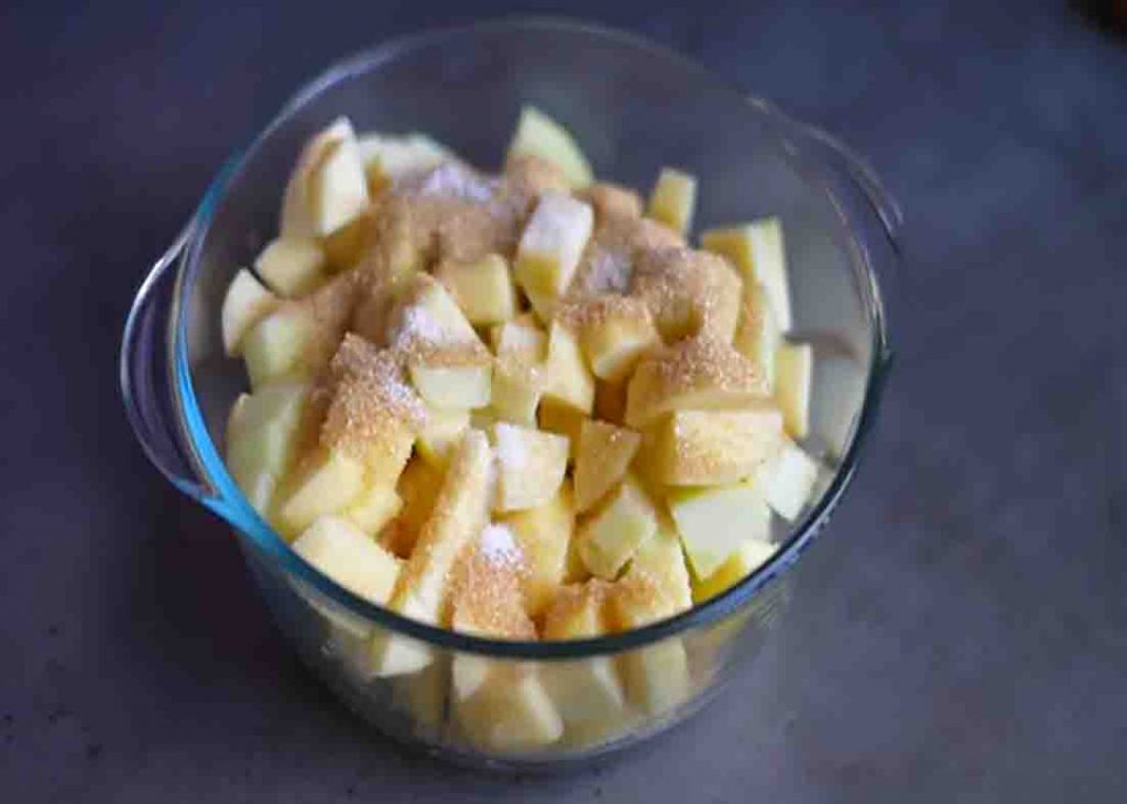 Adding sugar and cinnamon to the apples for the apple crumble recipe