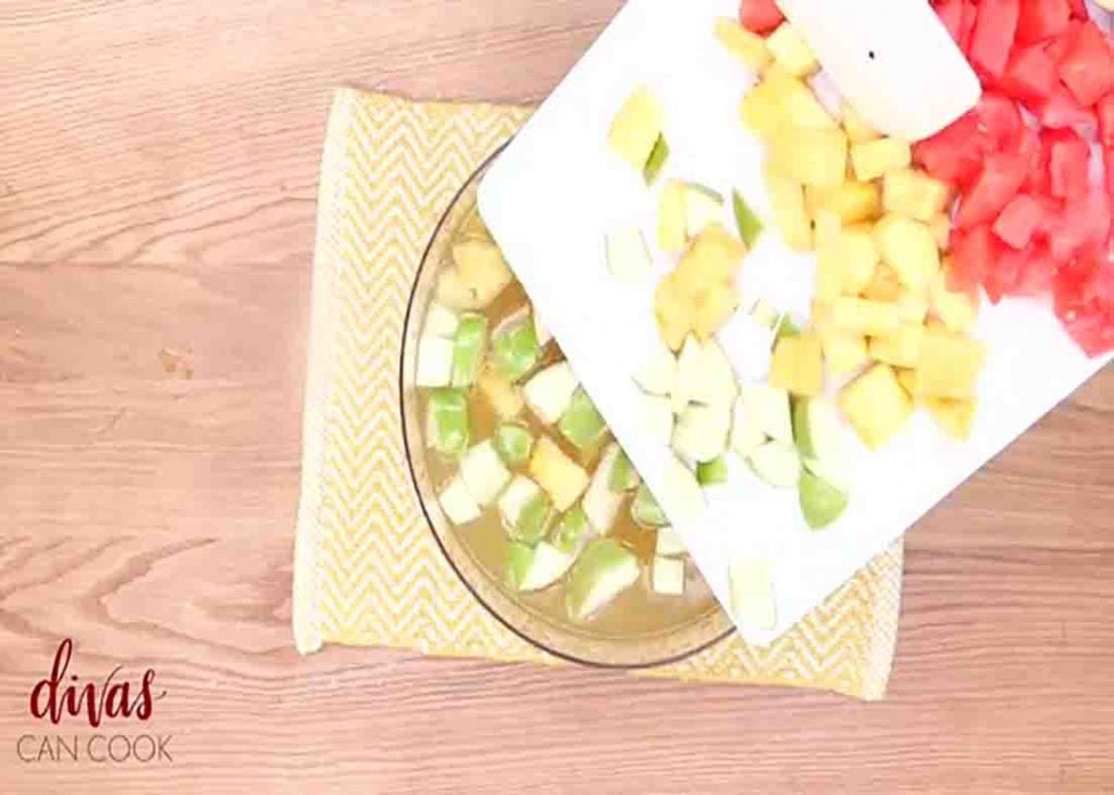 Adding the fruit slices to the fruity cocktail punch