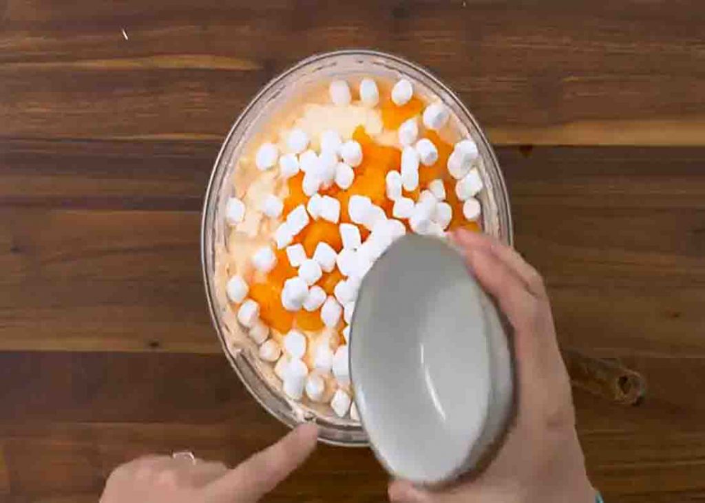Adding the orange and marshmallows to the salad