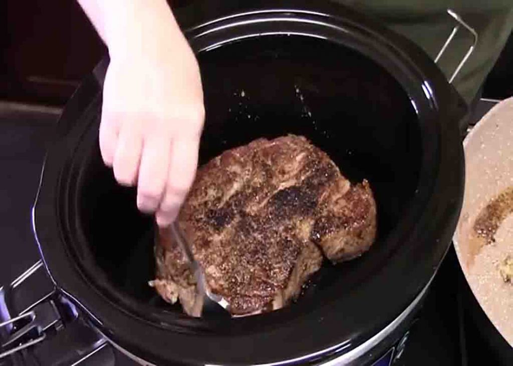 Transferring the chuck roast to the crockpot