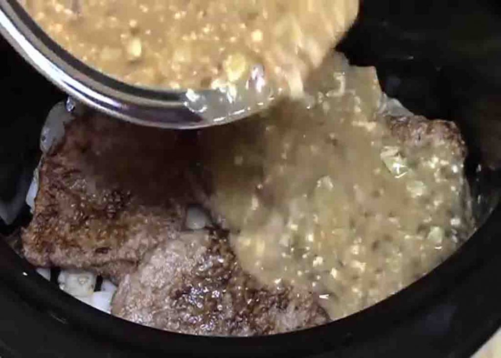Adding the gravy sauce to crockpot with the cube steaks