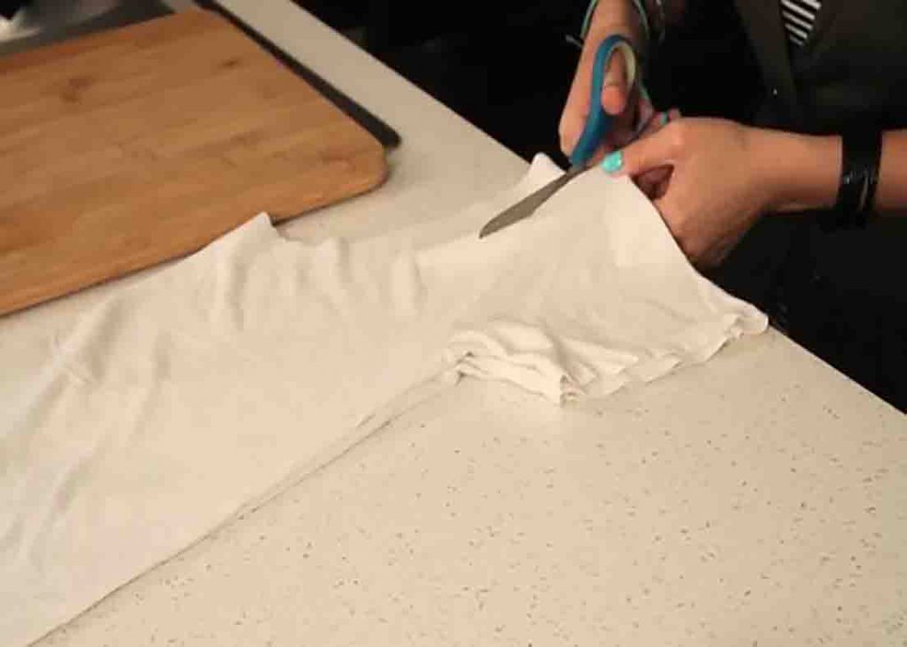 Cutting the sleeves of the t-shirt to make it into a tote bag