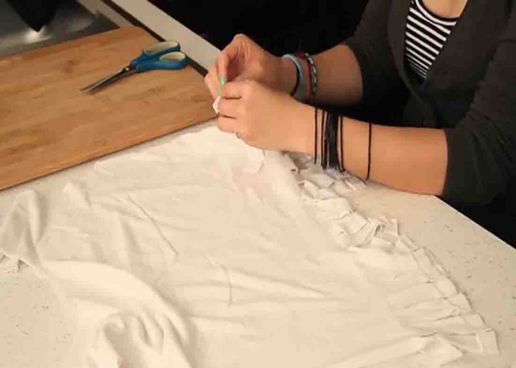 Finishing the DIY tote bag by knotting the ends of the t-shirt