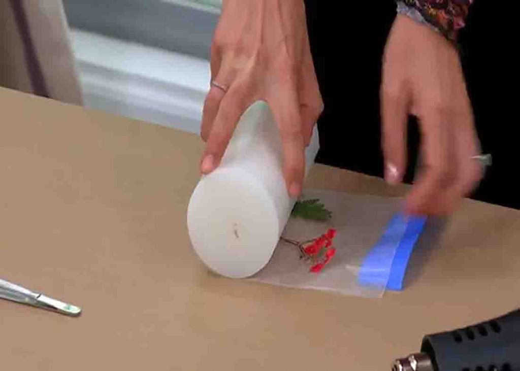 Attaching the pressed flowers to the candle using wax paper