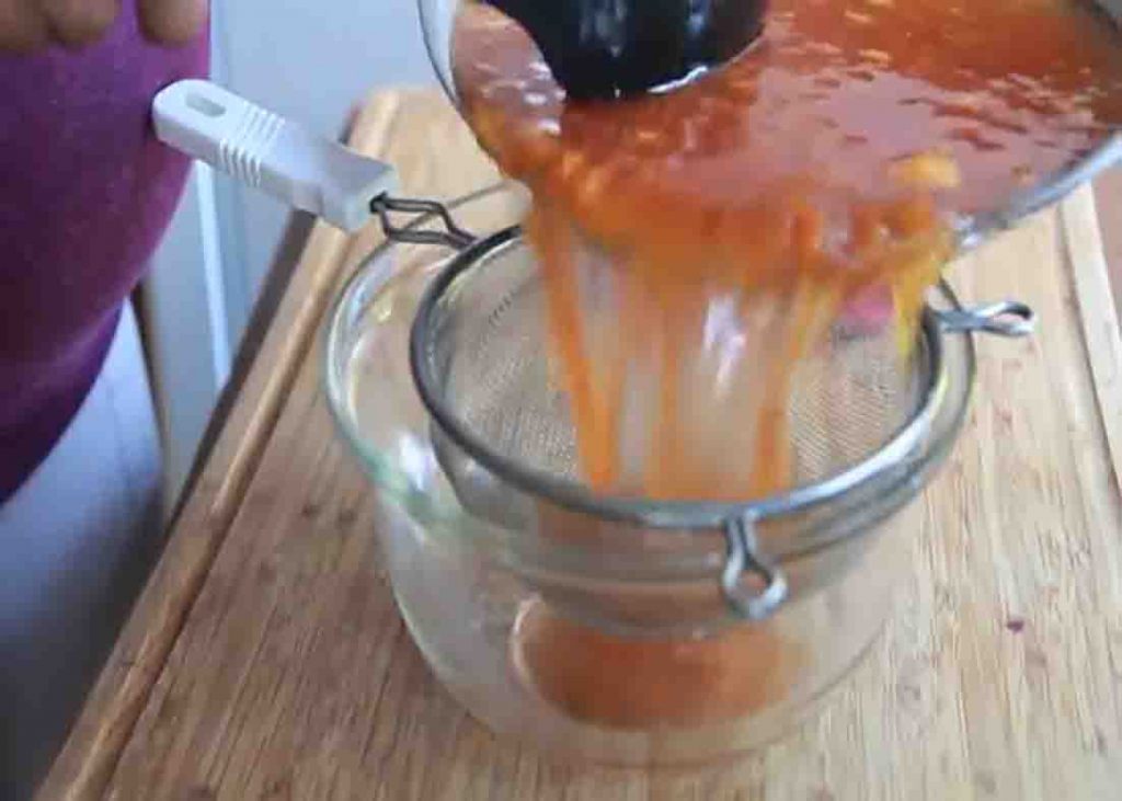 Straining the peach syrup to remove pulp and skin