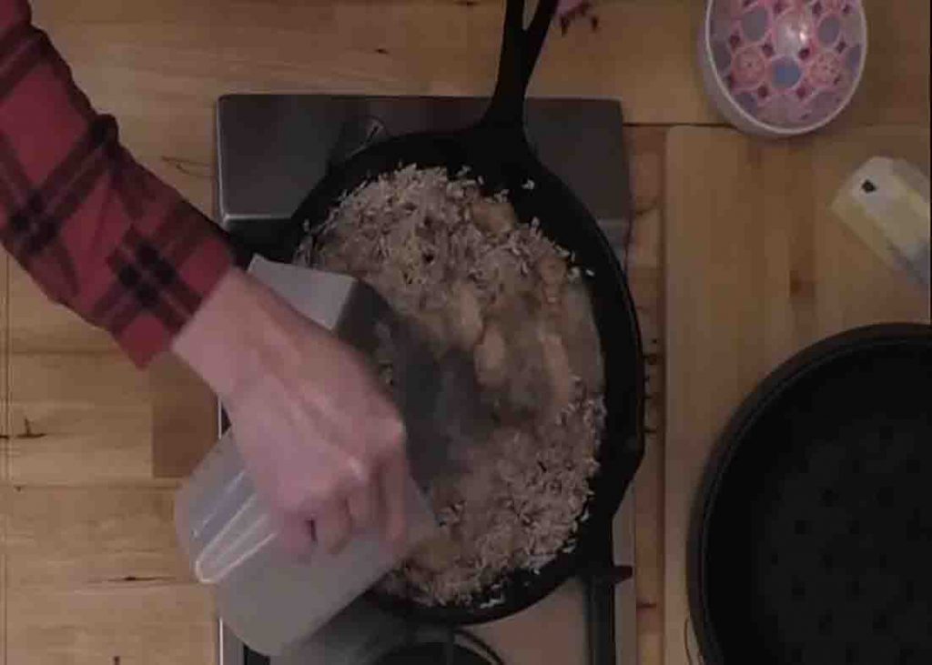 Adding water to the chicken and rice skillet